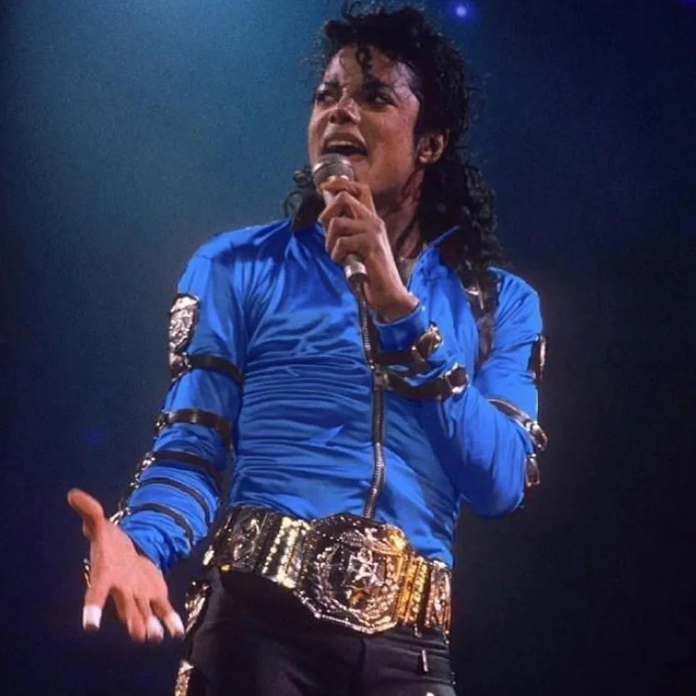 Person in a blue outfit with metallic accents holding a microphone on a dark background
